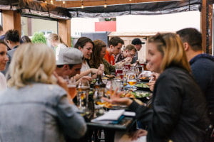 Viele Personen die an einem Strand an einem großen Tisch sitzten und sich unterhalten und essen