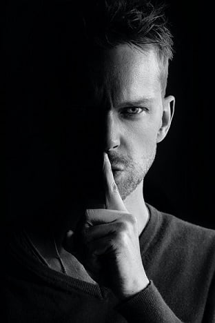Schwarz Weiß Foto von Mann der Finger auf Lippen legt zum Schweigen